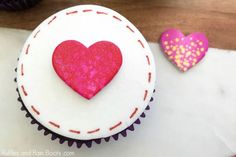 two cupcakes with pink and red frosting in the shape of a heart