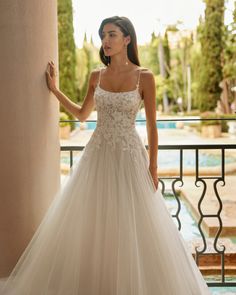 a woman in a wedding dress standing on a balcony with her hand on the wall