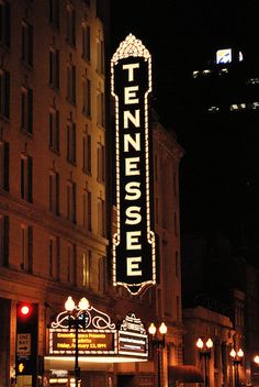 a theater marquee lit up at night in the middle of a city street