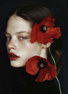 a woman with red flowers on her head and eyes, in front of a black background