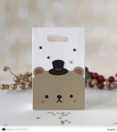 a brown bear with a black hat on its head is in a white paper bag