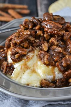 a bowl filled with mashed potatoes covered in pecans and sauce on top of a blue towel