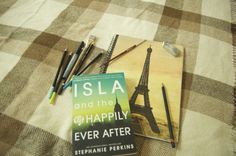 a book sitting on top of a bed next to some pens and markers in front of the eiffel tower