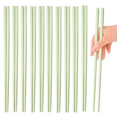 a hand reaching for chopsticks that are green