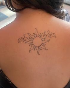 the back of a woman's shoulder with a sun tattoo on her upper arm