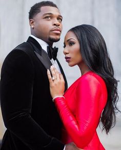 a man in a tuxedo standing next to a woman wearing a red dress