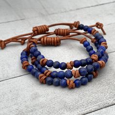 Rustic brown leather and blue Lapis Lazuli gemstones. The Lapis stones have beautiful blue color and are flecked with golden pyrite. They are small 5-6mm stones with a matte finish. These bracelets look great alone or stacked together and with other bracelets. The classic look of gemstones with modern and edgy leather. Groups of three gemstones knotted together around a leather bracelet. Finished with a sliding knot clasp. The clasp adjusts to help you get the perfect fit. Slide the leather knot Adjustable Leather Bracelets With Natural Stones, Adjustable Lapis Lazuli Beaded Bracelets Bohemian Style, Handmade Spiritual Leather Bracelet With Round Beads, Rustic Blue Adjustable Beaded Bracelets, Adjustable Blue Earthy Jewelry, Rustic Adjustable Blue Beaded Bracelet, Rustic Blue Adjustable Beaded Bracelet, Leather Bracelets With Natural Stones For Gifts, Artisan Blue Adjustable Wrap Bracelet