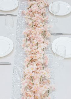 the table is set with white plates and pink flowers