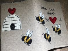 two bees are on the side of a piece of fabric with embroidered words and hearts