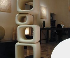 a large white vase sitting on top of a black table next to a tall sculpture