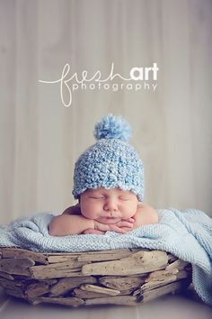 a baby is laying in a basket wearing a blue hat