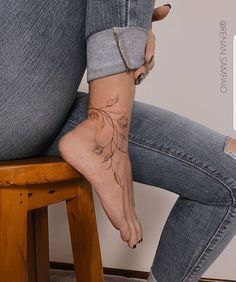 a woman sitting on top of a wooden stool with her foot up to the ground