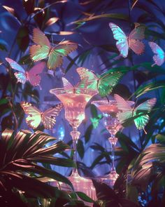 three wine glasses with butterflies on them sitting in front of some green plants and leaves