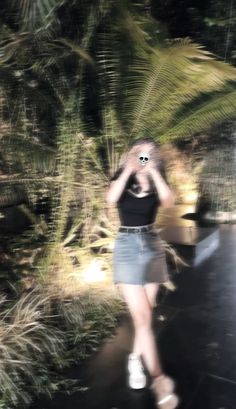 a blurry image of a woman walking down a path with her hand on her head