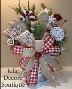 a christmas arrangement in a bucket with red, white and silver decorations on it that says jolie decore boutique