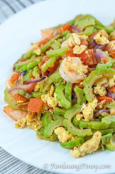 a white plate topped with vegetables and shrimp