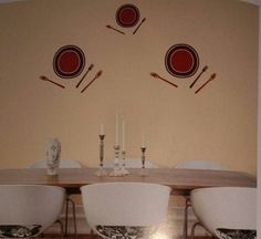 a dining room table with chairs and plates on the wall above it is decorated with red circles