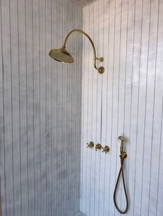 a shower head and hand shower in a bathroom with striped wallpaper on the walls