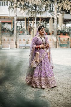 a woman in a purple and gold bridal gown posing for the camera with her hands on her hips