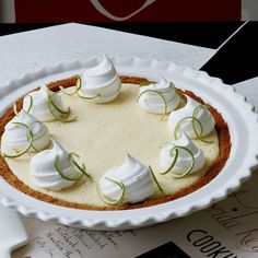 a white plate topped with a cheesecake covered in whipped cream and green onion garnish