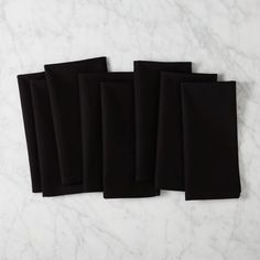 five black napkins sitting on top of a white counter