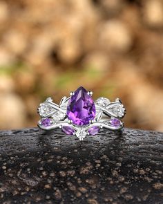 an amethoraite and diamond ring sitting on top of a rock