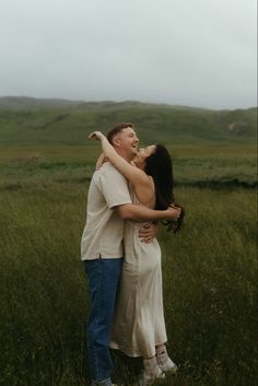 a man and woman hugging in the middle of a field