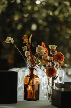 two vases filled with flowers sitting on top of a white tablecloth covered table