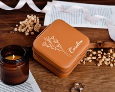 a candle sitting next to a jar and some paper on a table with flowers in it