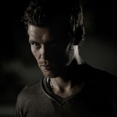 a man in a dark room looking at the camera with an intense look on his face