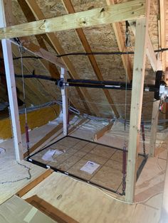 an unfinished attic with exposed rafters and wood flooring on the walls, along with other construction materials