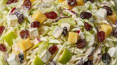 a salad with apples, cranberries, cheese and dressing on it is shown