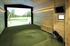 an indoor golf course with wooden walls and green grass