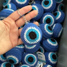 a hand is holding a keychain made out of blue and white crocheted balls