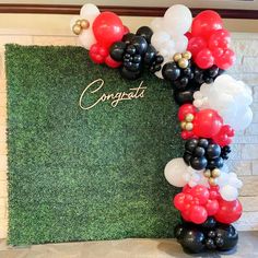 the balloon arch is decorated with black, white and red balloons that spell congratulations in gold lettering