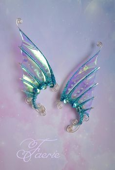 two blue and green fairy wings on a pink background