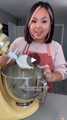 a woman in an orange apron is making some kind of cake with a yellow mixer