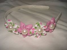 a headband with pink flowers and pearls on the side, sitting on a bed