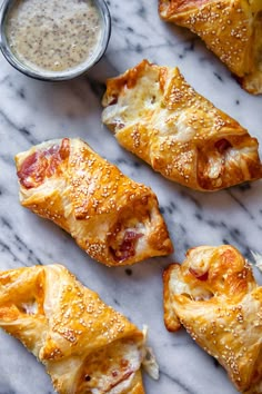 several pieces of pastry on a marble surface with dipping sauce in the middle and one piece cut out