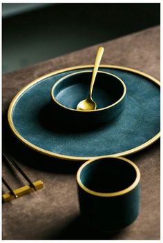 a place setting with gold rimmed dishes and chopsticks