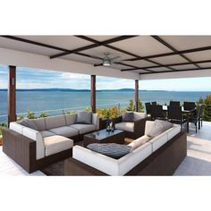 an outdoor living area with couches, tables and water view from the deck overlooking the ocean