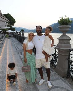 a man, woman and child posing for a photo on the waterfront with water in the background