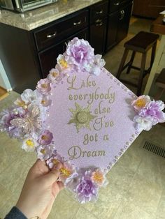 someone holding up a pink graduation cap with flowers on it that says, like everybody else got a dream