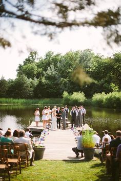 the wedding party is on the dock by the water and people are waiting to get married