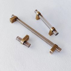 three metal handles on a white surface, one is gold and the other is silver