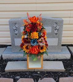 an arrangement of flowers is placed in front of a grave