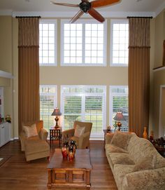 a living room with couches, chairs and a ceiling fan in the middle of it