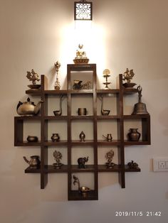 a shelf filled with pots and vases on top of wooden shelves next to a wall light