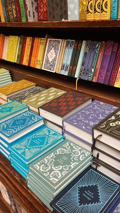 many books are stacked on top of each other in front of a book shelf full of them