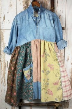 a dress hanging on a wooden wall with an old fashioned button up shirt over it